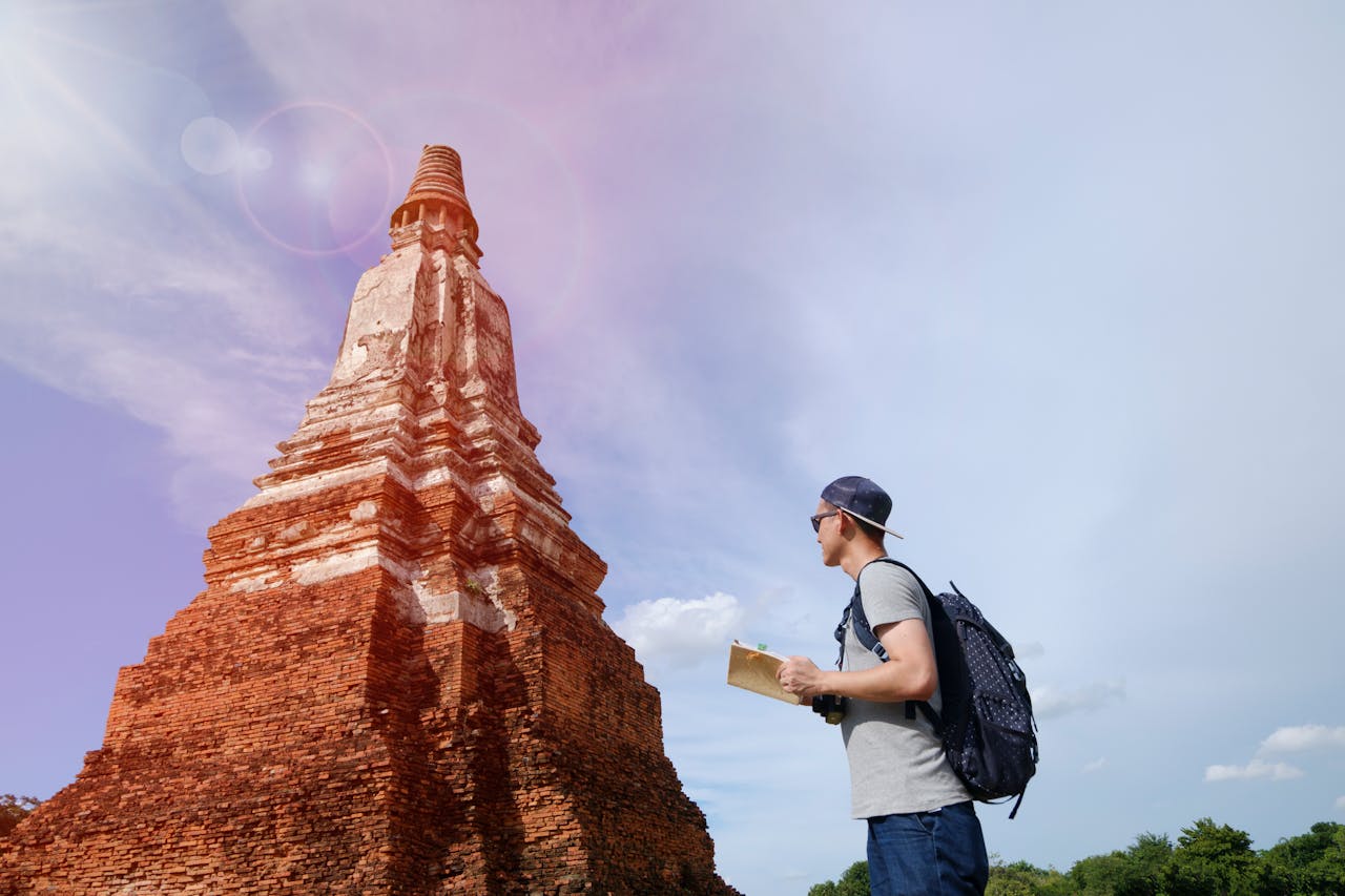 A young traveler with a backpack examines ancient temple ruins under a clear sky, capturing a serene adventure.