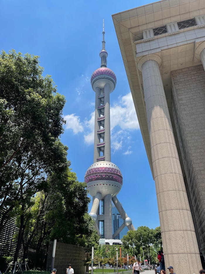 View of Shanghais Oriental Pearl Tower with surrounding modern architecture and lush greenery.